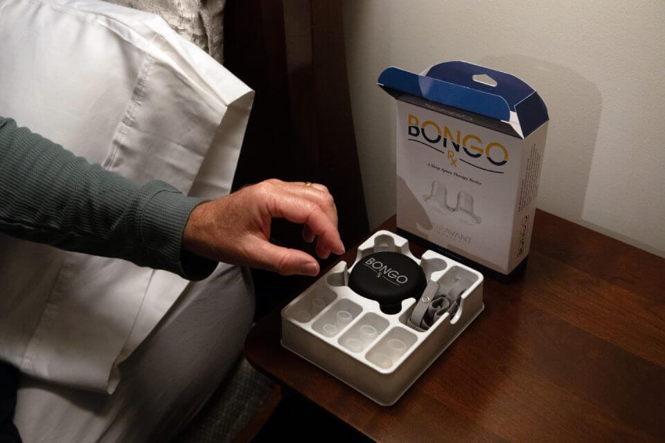 A hand reaching for the Bongo Rx 4-in-1 Starter Fit Kit by the bedside